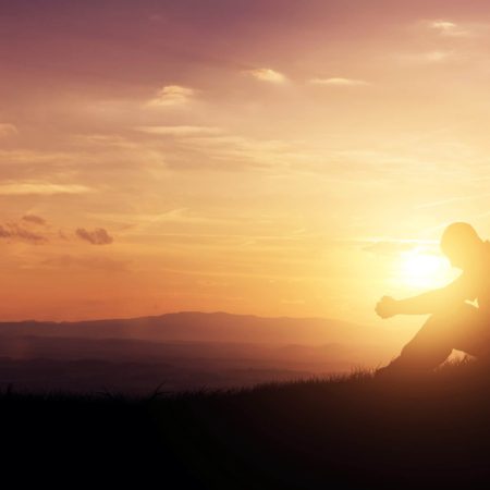 Silhouette of a man praying on a hill