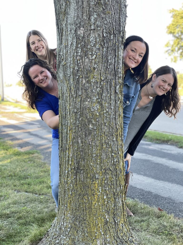 the women's ministry team behind a tree